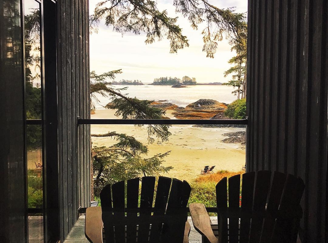Two wooden chairs on a deck look out to the ocean at the The Wickaninnish Inn .