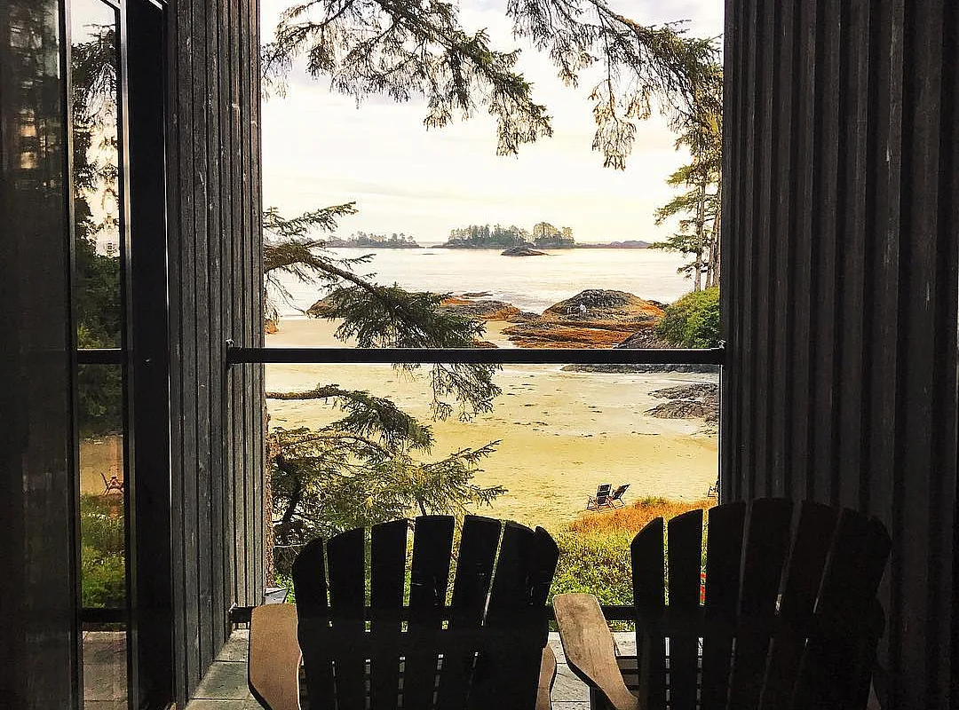 Two wooden chairs on a deck look out to the ocean at the The Wickaninnish Inn .