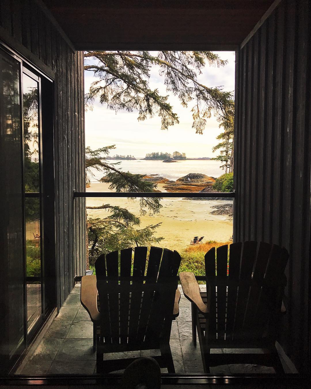 Two wooden chairs on a deck look out to the ocean at the The Wickaninnish Inn .