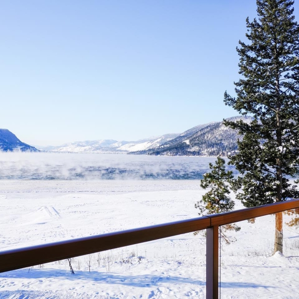 Snowy views from the patio at Quaaout Lodge looking out into a vast empty field with mountains in the distance.