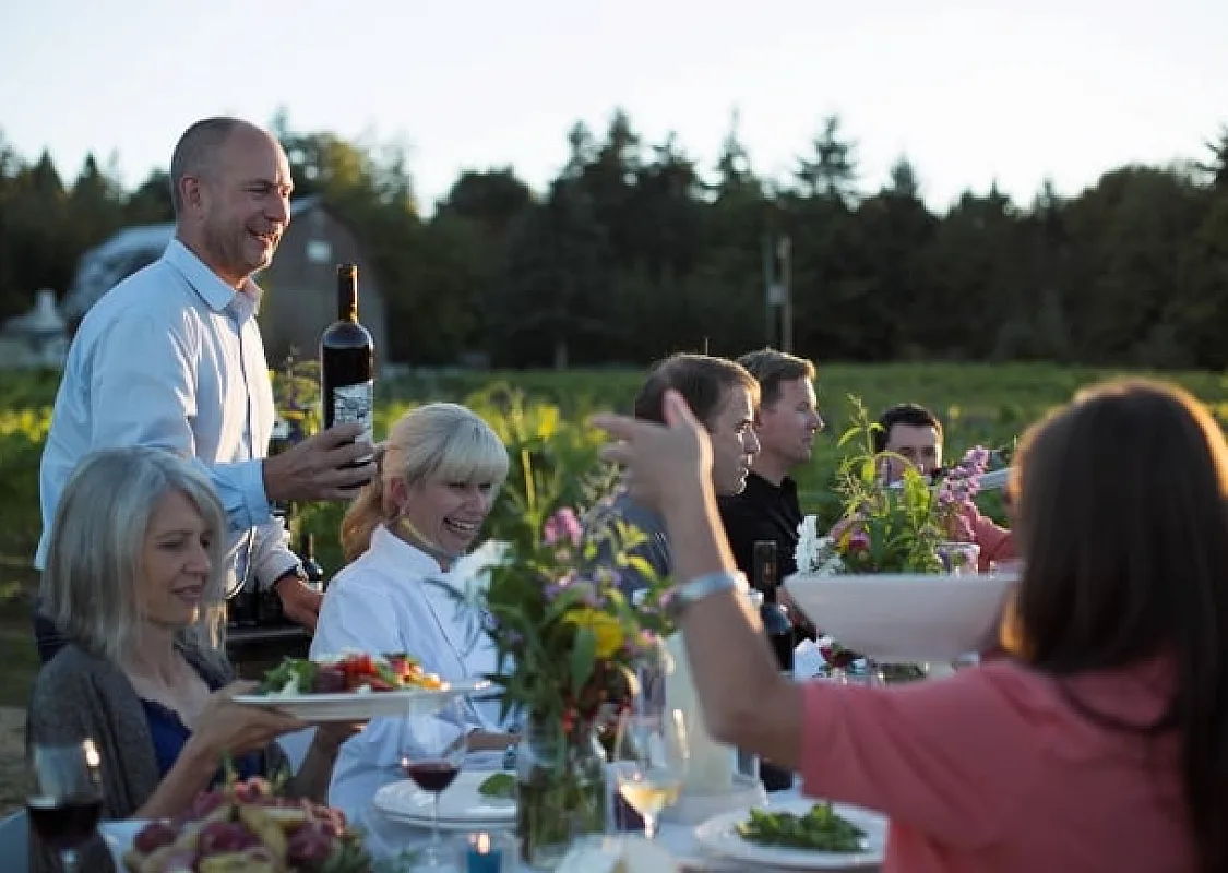Al fresco dining with a large group at a long table in the summer at Vista D'oro Vineyard in Langley.