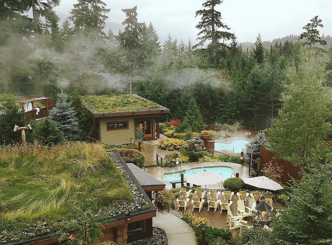 Scandinave Spa Whistler during the day time. Several pools are scattered throughout the property, surrounded by treese.
