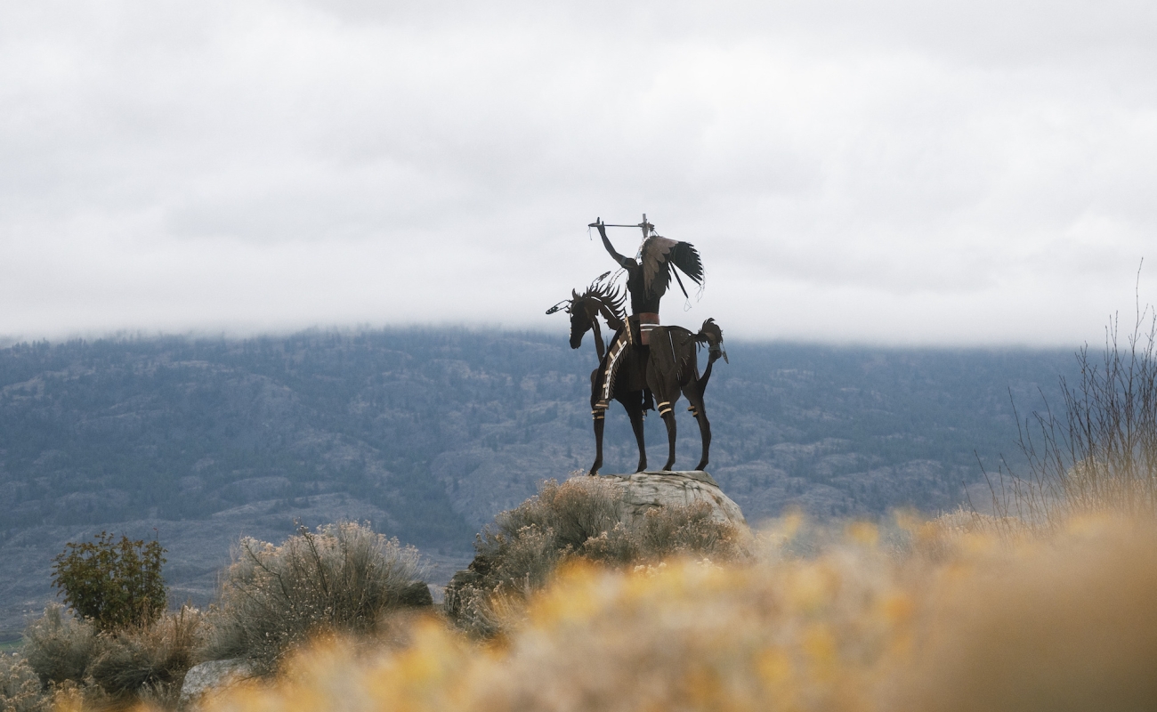 An Indigenous horserider statue overlooks the Okanagan landsdcapes.