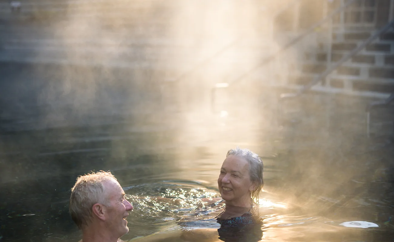 Una pareja sonriente se relaja en las Liard River Hot Springs.