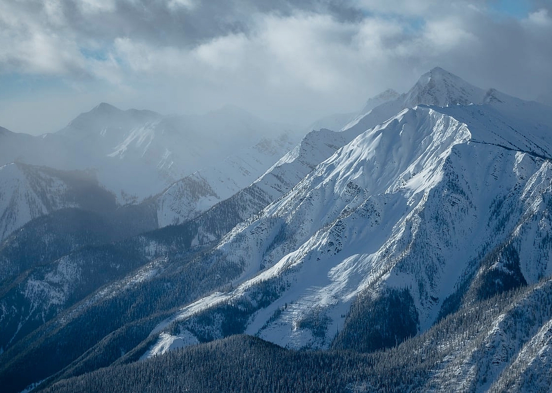 A snowy and foggy mountain landscape with jagged mountain peaks.