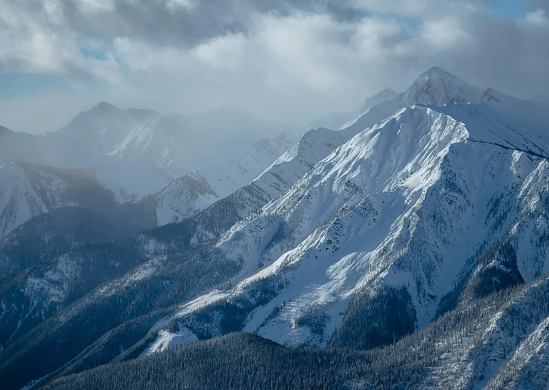 A snowy and foggy mountain landscape with jagged mountain peaks.