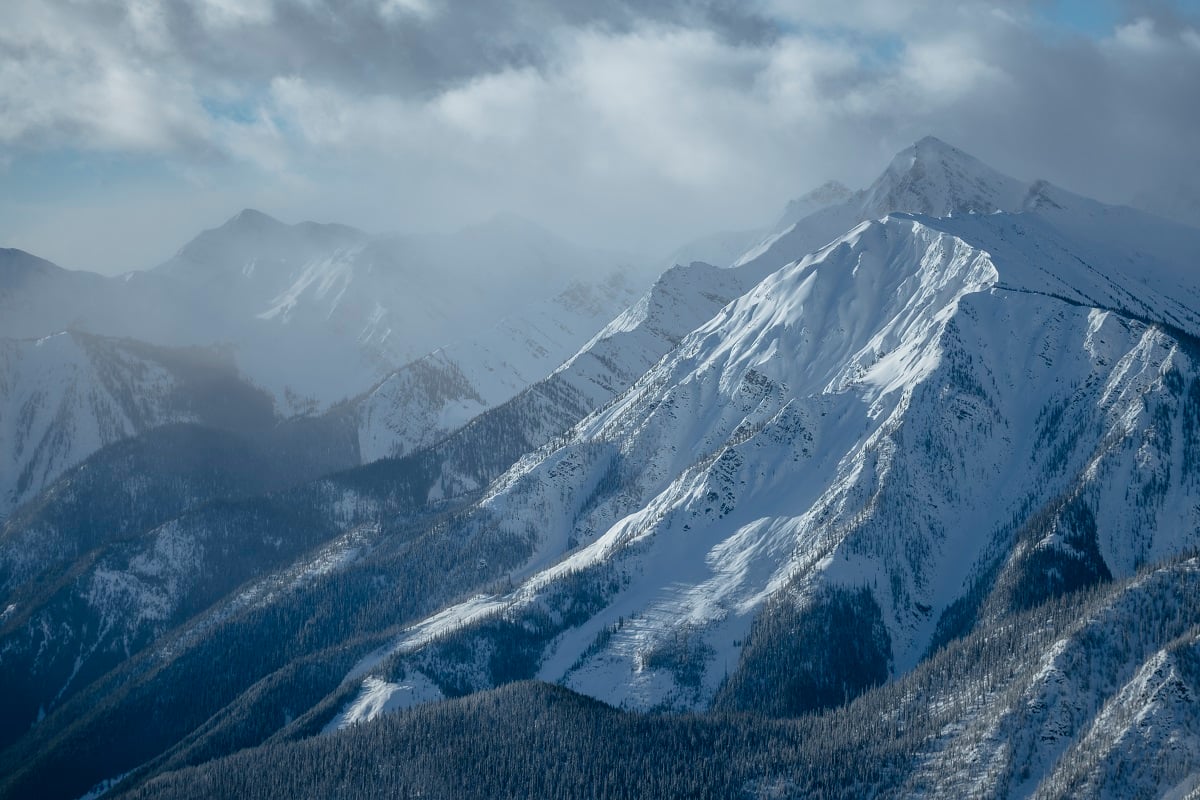 A snowy and foggy mountain landscape with jagged mountain peaks.