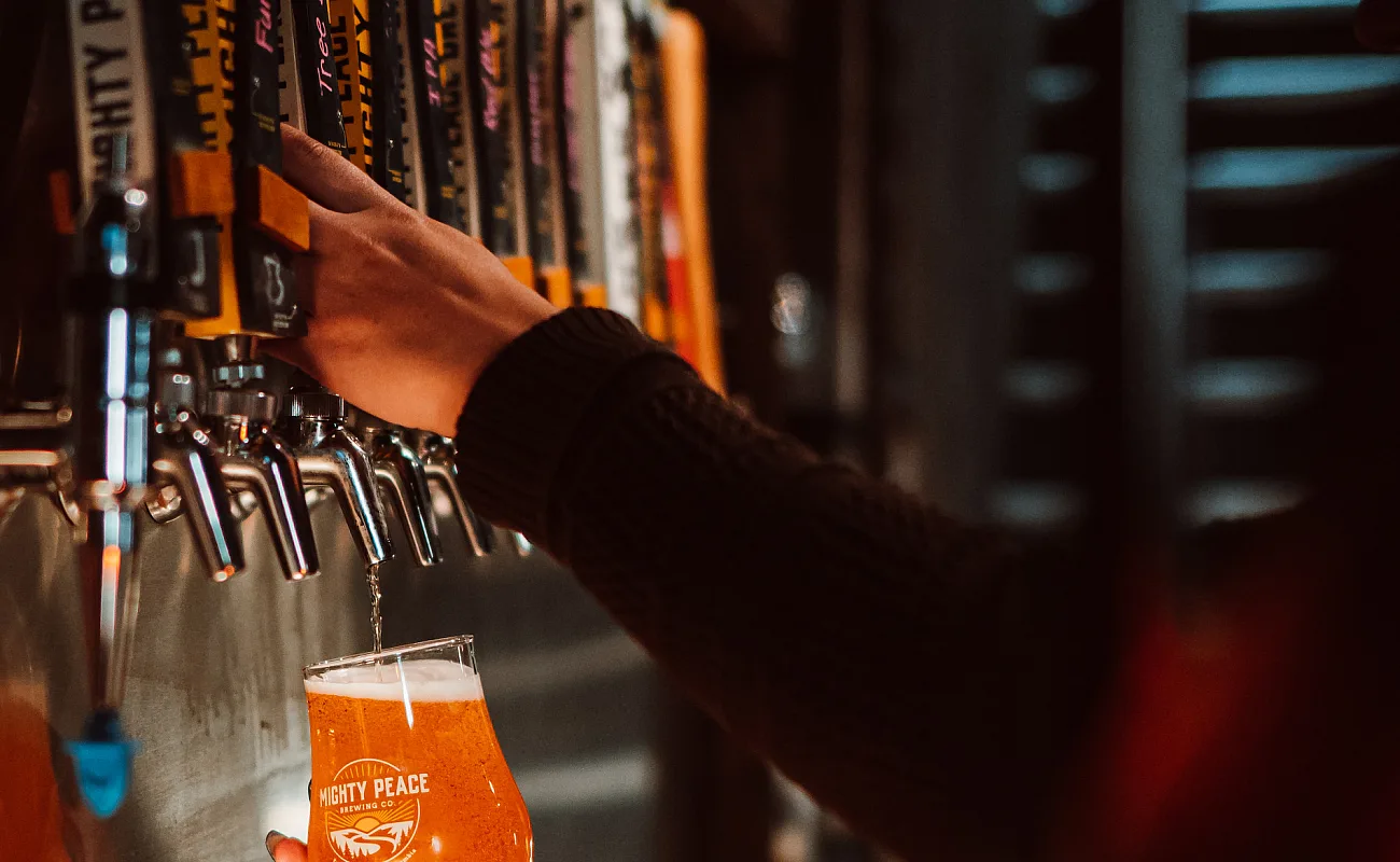Una persona sirve una pinta fría de cerveza de los grifos de Mighty Peace Brewery en Fort St. John.