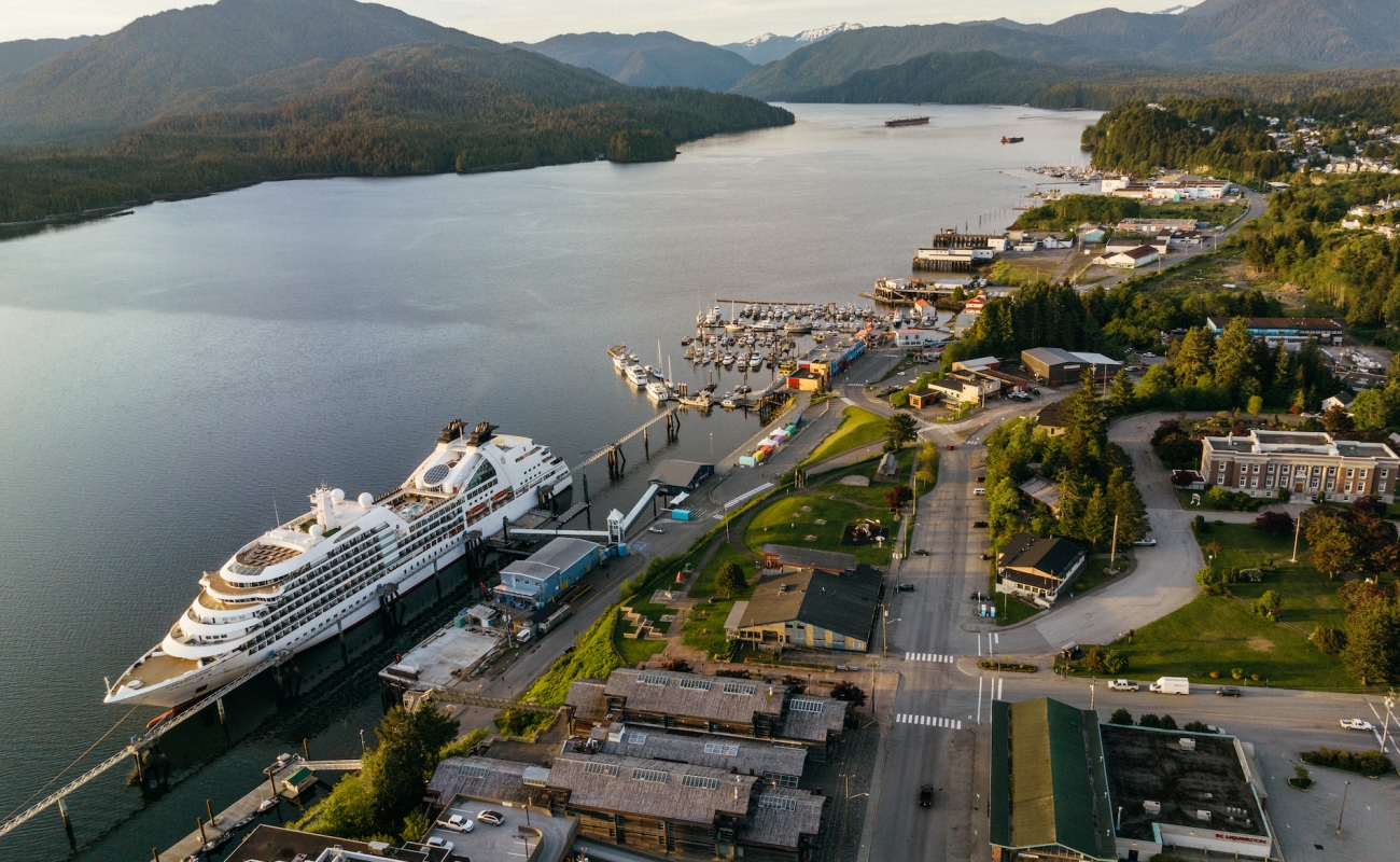 Eine Luftaufnahme eines Kreuzfahrtschiffes, das im Hafen von Prince Rupert vor Anker liegt, mit dem Pazifischen Ozean und Bergen im Hintergrund.