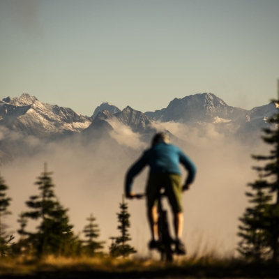 Ein Mountainbiker auf dem Friendly Giant Trail in Kaslo mit Berge in der Ferne.