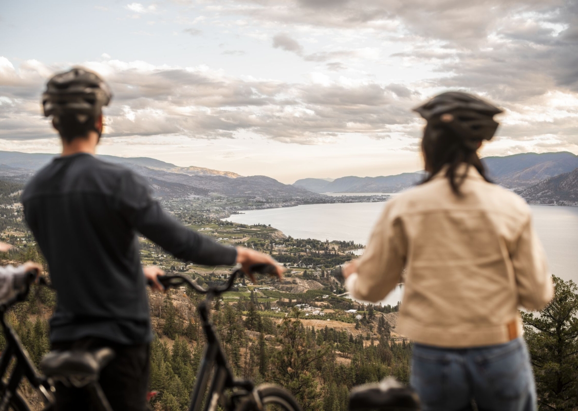 A couple enjoying the view of Naramata and Okanagan Lake during their bike ride along the Kettle Valley Rail Trail.