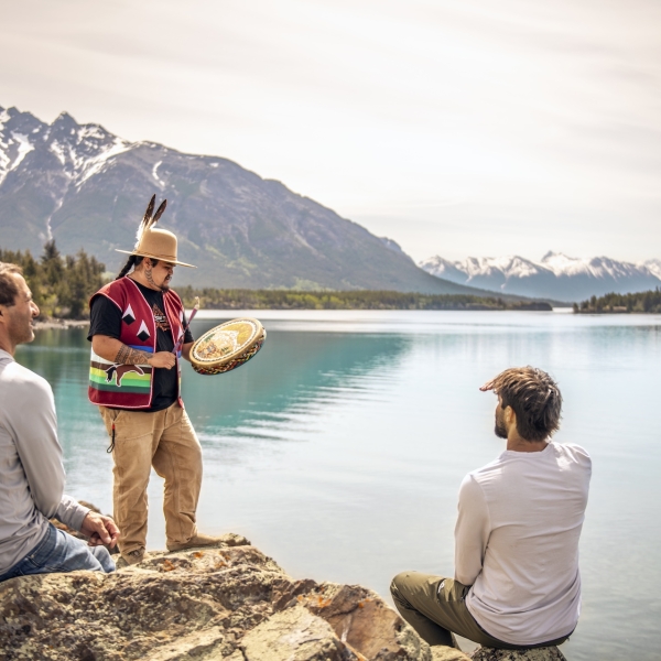 Ein*e indigene*r Reiseführer*in singt ein Lied für Besucher*innen auf dem Nu Chugh Beniz Campingplatz im Ts'il?os Park, neben dem Chilko Lake, BC.