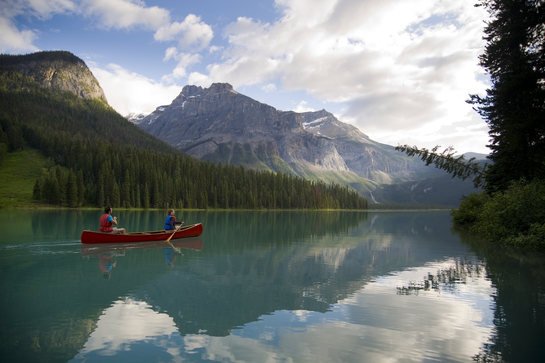 Two people canoeing on Emerald Lake with views of the mountains in Yoho National Park near Field.