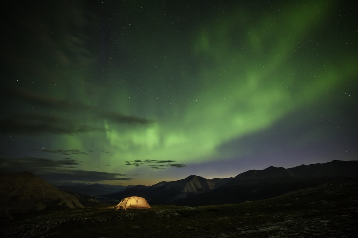 Una tienda de campaña iluminada bajo las auroras boreales.