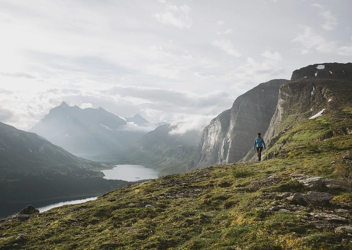 A hiker surrounded by towering mountains and alpine lakes.