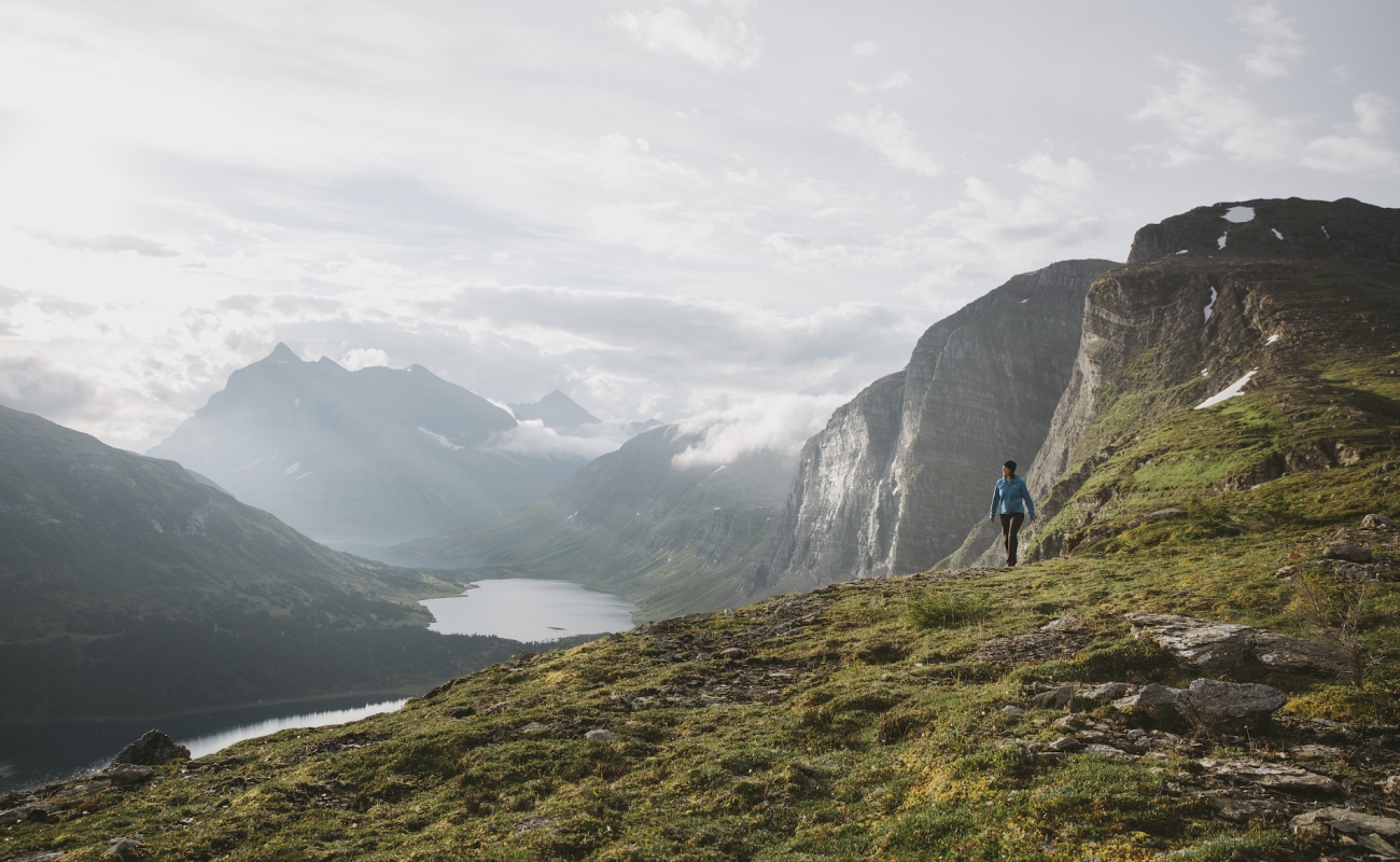 A hiker surrounded by towering mountains and alpine lakes.