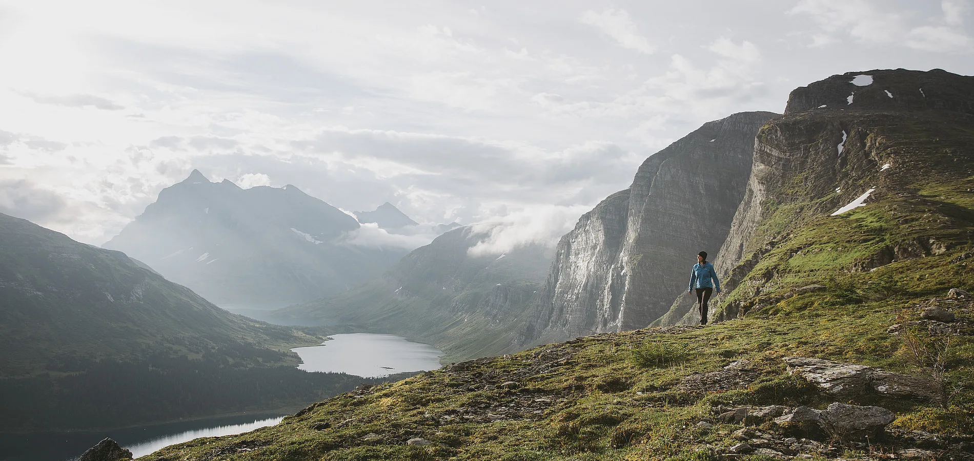 Ein*e Wander*in, umgeben von hoch aufragenden Bergen und Alpenseen.