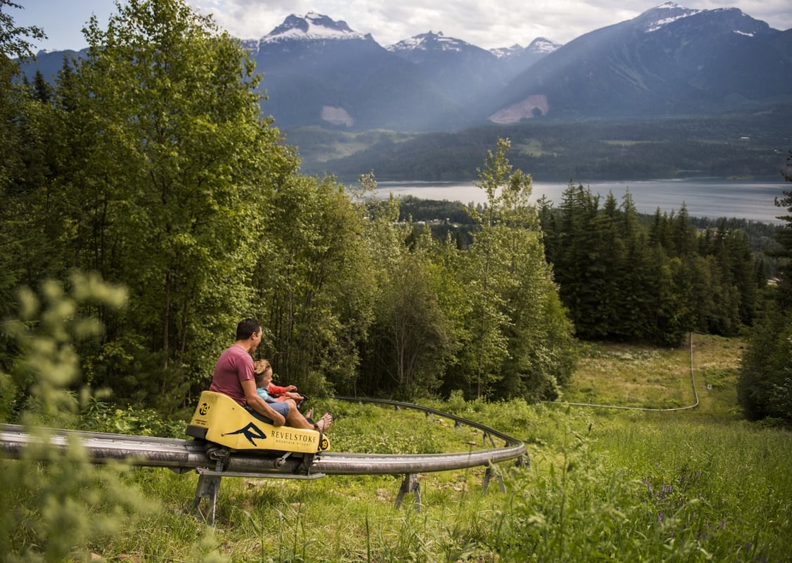 Ein Elternteil und ein Kind genießen den Pipe Mountain Coaster im Revelstoke Mountain Resort in Revelstoke, BC.