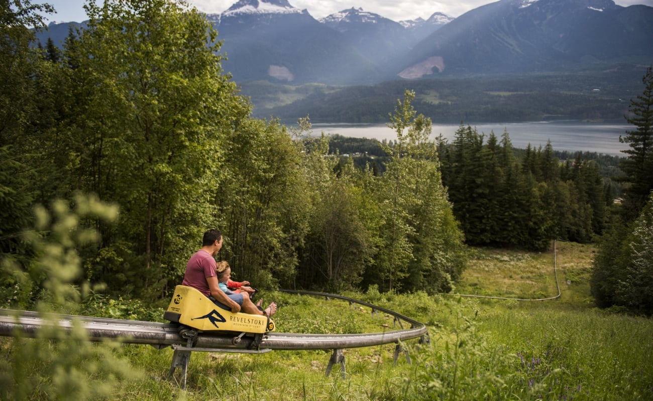 Ein Elternteil und ein Kind genießen den Pipe Mountain Coaster im Revelstoke Mountain Resort in Revelstoke, BC.