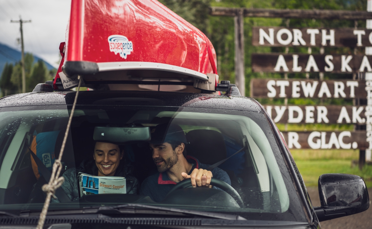 Two people in a car with a canoe on top
