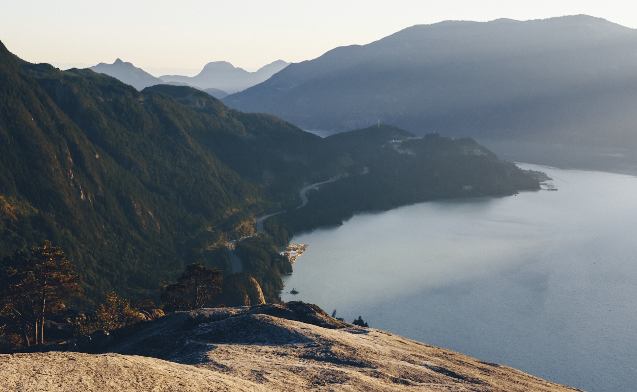 Vista desde la cima de un enorme monolito de granito con vista al océano y las montañas.