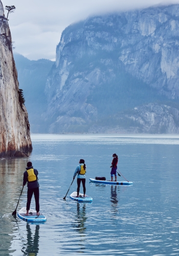 Three paddleboarders surrounded by massive rocks.