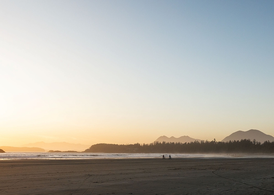 A couple enjoying a bike ride on their rental bikes at North Chesterman Beach in Tofino.
