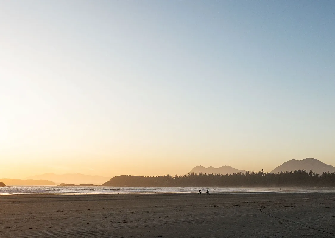 A couple enjoying a bike ride on their rental bikes at North Chesterman Beach in Tofino.