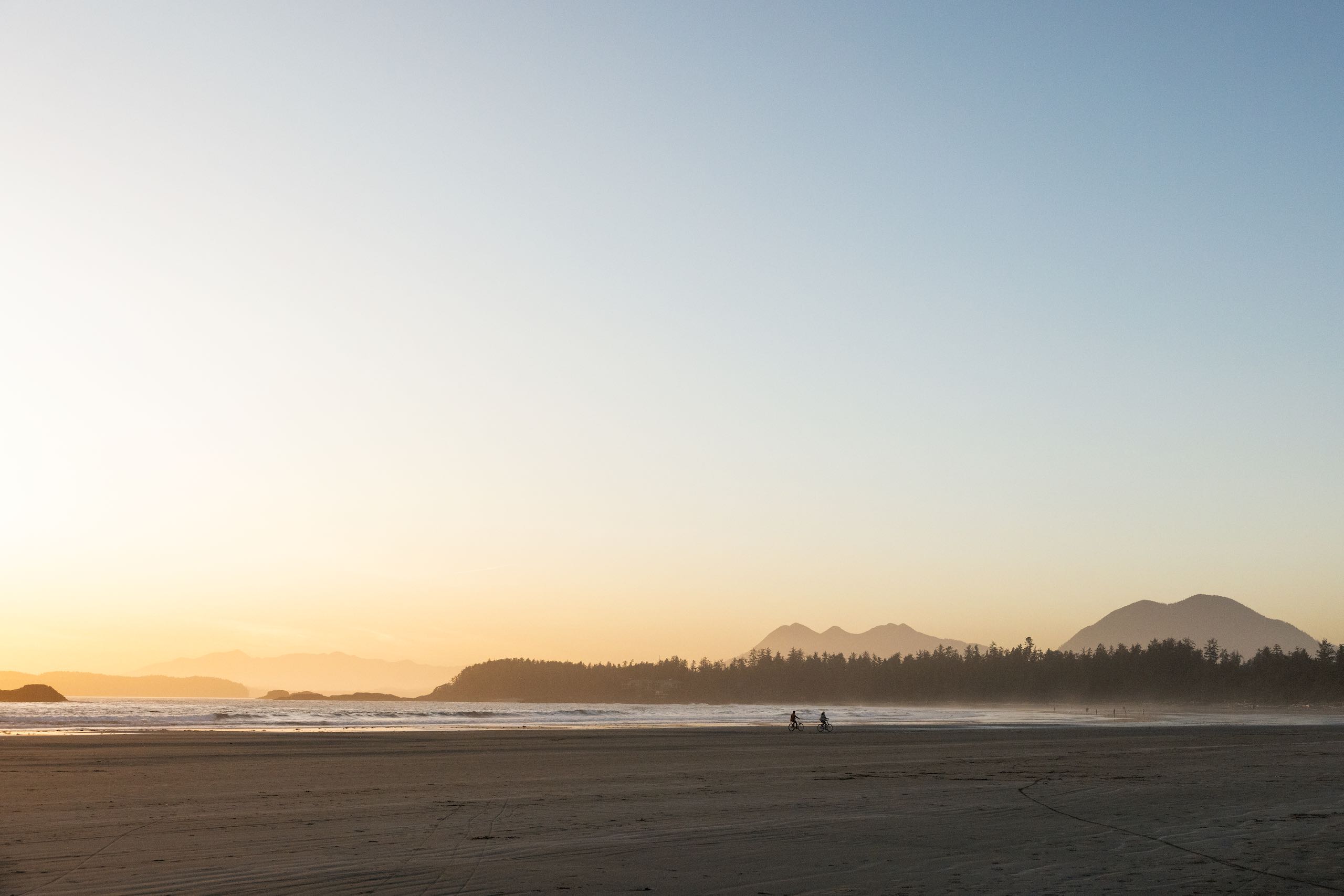 A couple enjoying a bike ride on their rental bikes at North Chesterman Beach in Tofino.