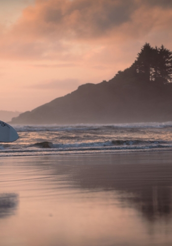 A man coming in from surfing Cox Bay