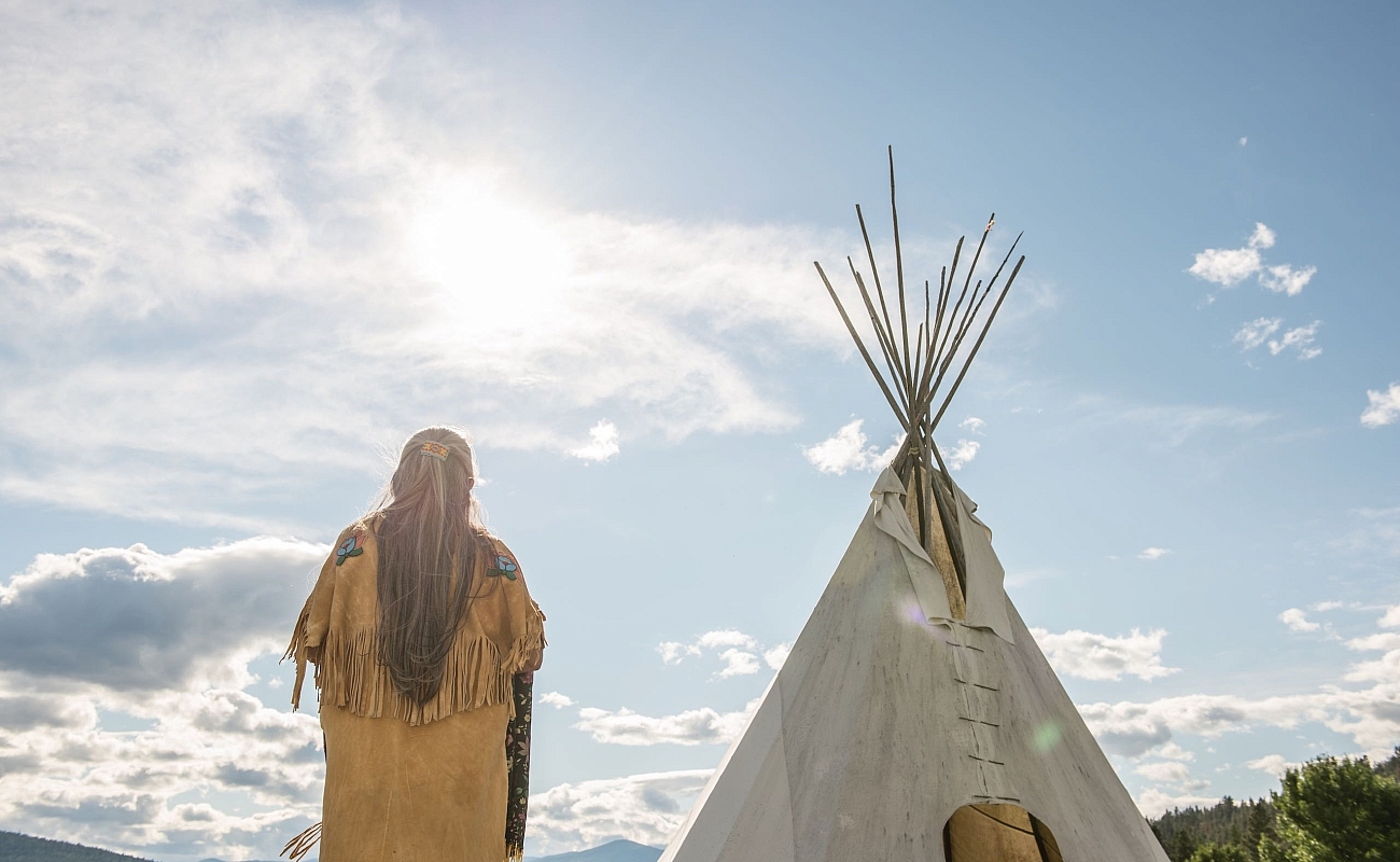 Ktunaxa elder in regalia next to a teepee at St Eugene Golf Resort