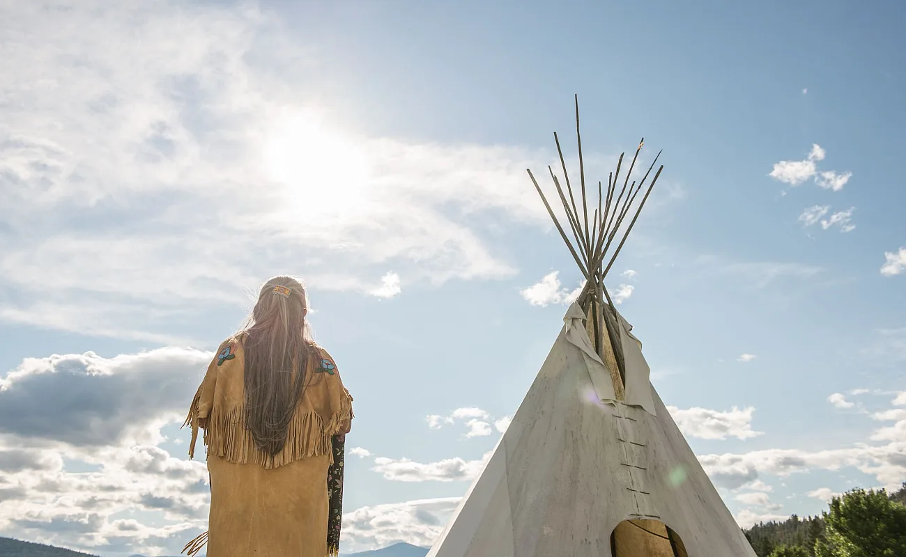 Ktunaxa elder in regalia next to a teepee at St Eugene Golf Resort