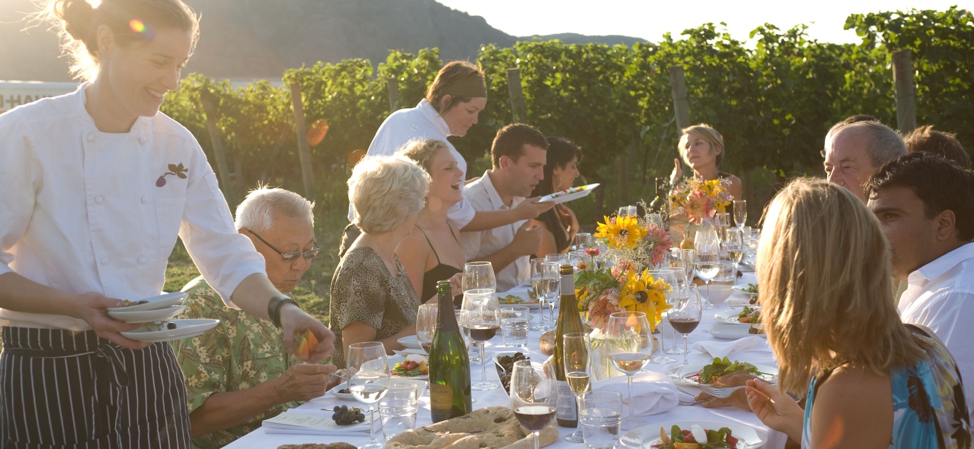 A group of people dining in the vineyard at Blue Mountain Vineyard and Cellars near Okanagan Falls.