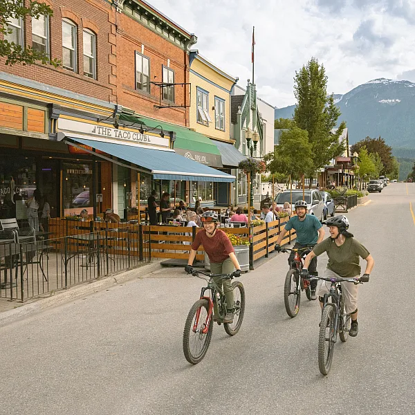 Three friends enjoy a bike ride in downtown Revelstoke as locals grab a bite to eat on The Taco Club patio.