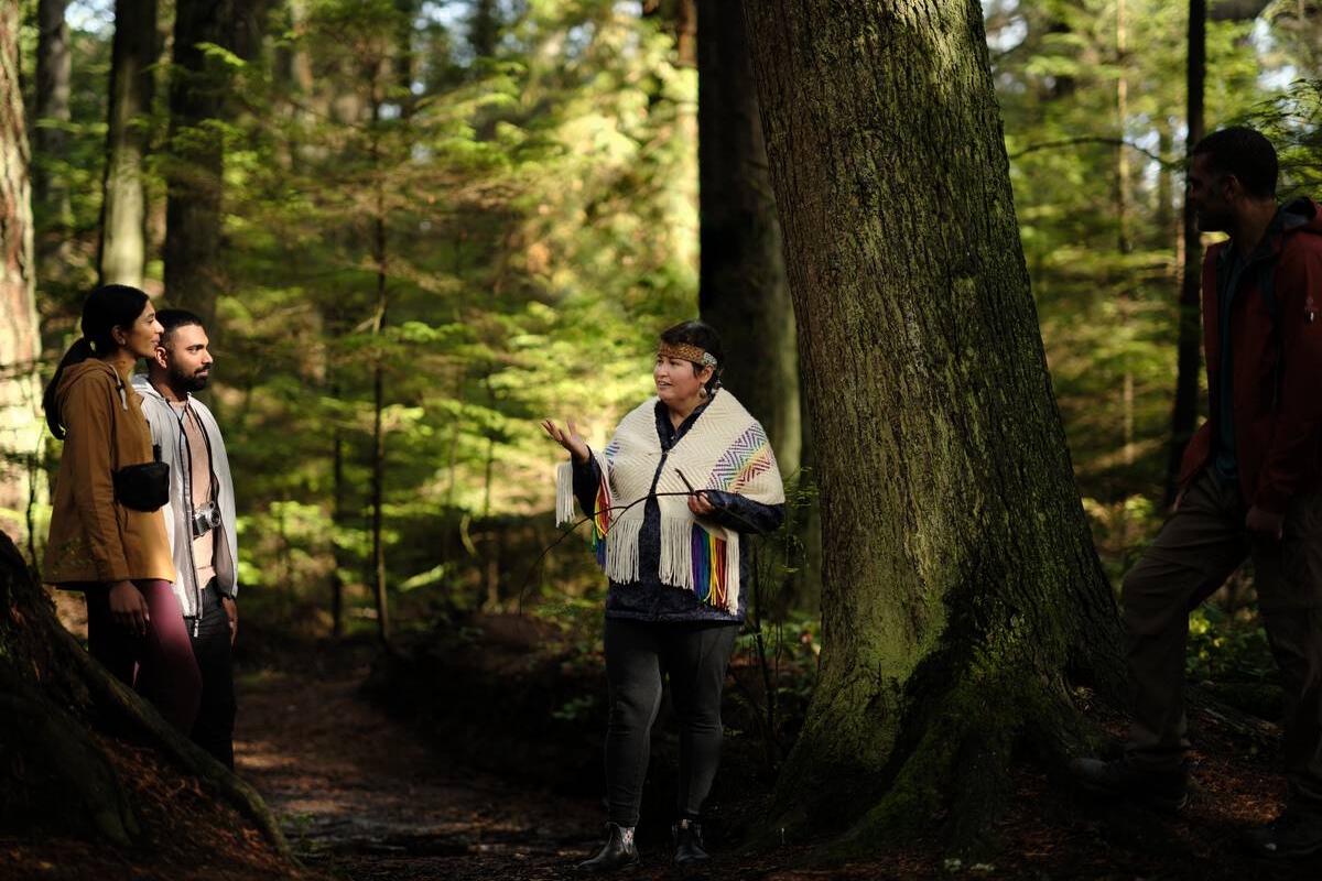 Candace Campo von Talaysay Walking Indigenous Tours hält eine Präsentation und spricht zu einer Gruppe während einer Wanderung im Stanley Park in Vancouver.