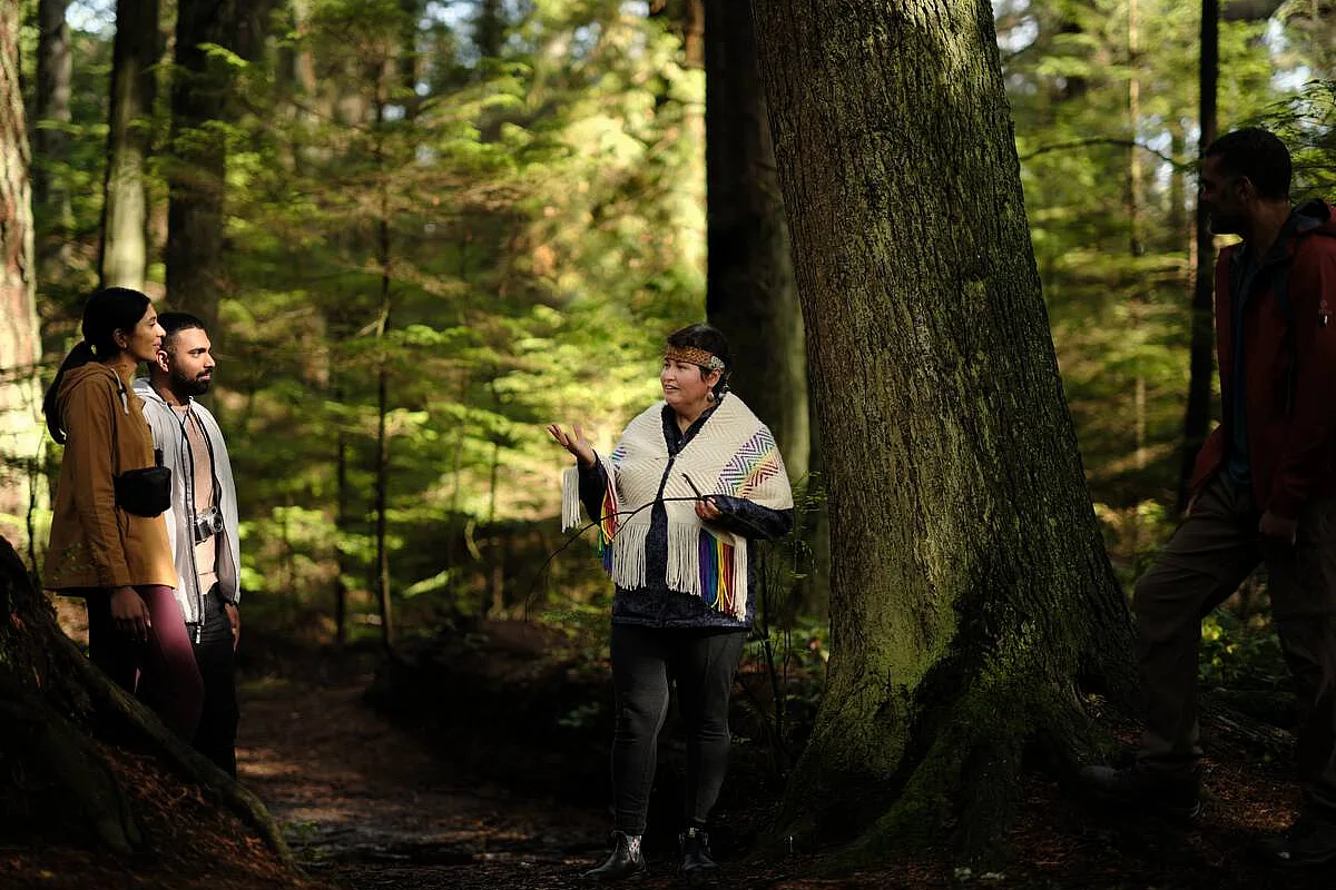 Candace Campo von Talaysay Walking Indigenous Tours hält eine Präsentation und spricht zu einer Gruppe während einer Wanderung im Stanley Park in Vancouver.