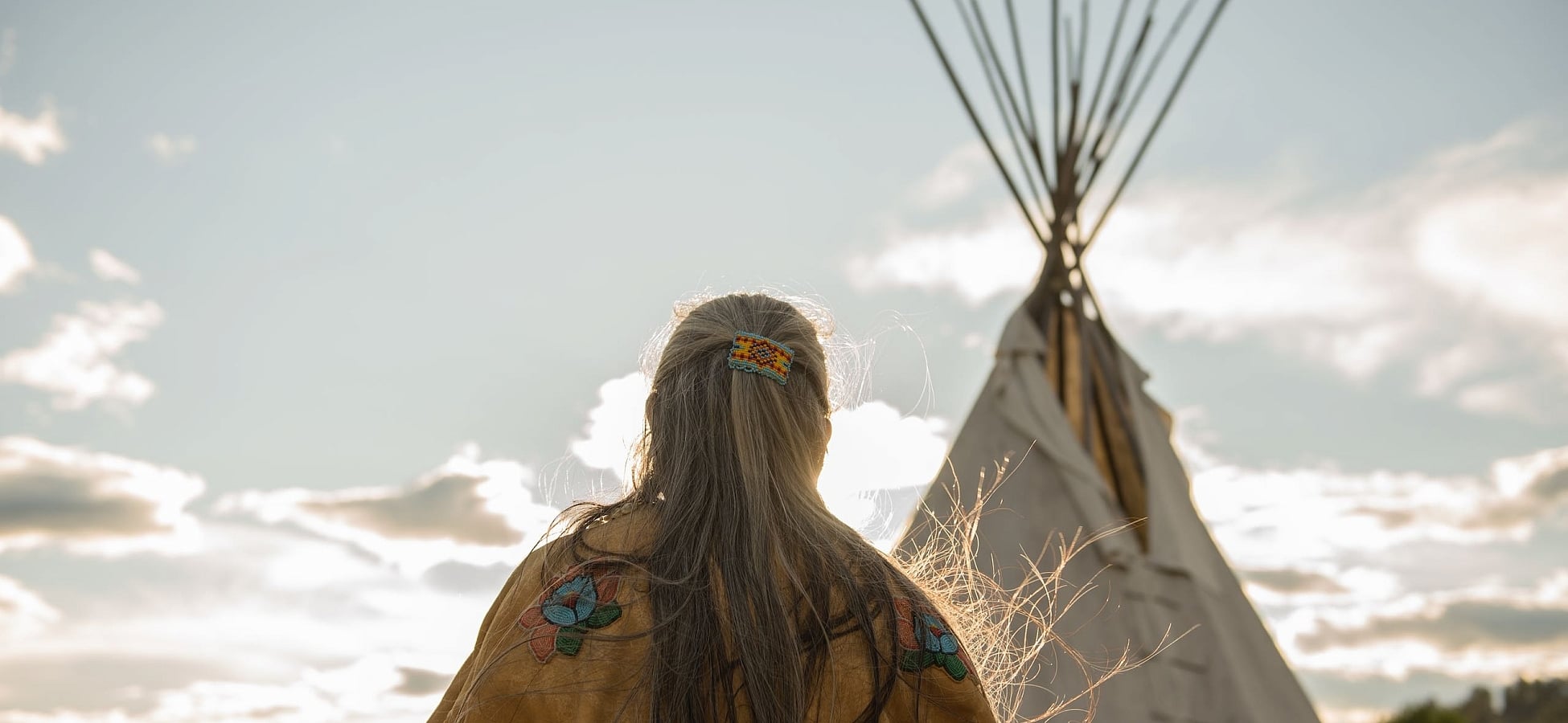 Ktunaxa elder in regalia next to a teepee at St Eugene Golf Resort