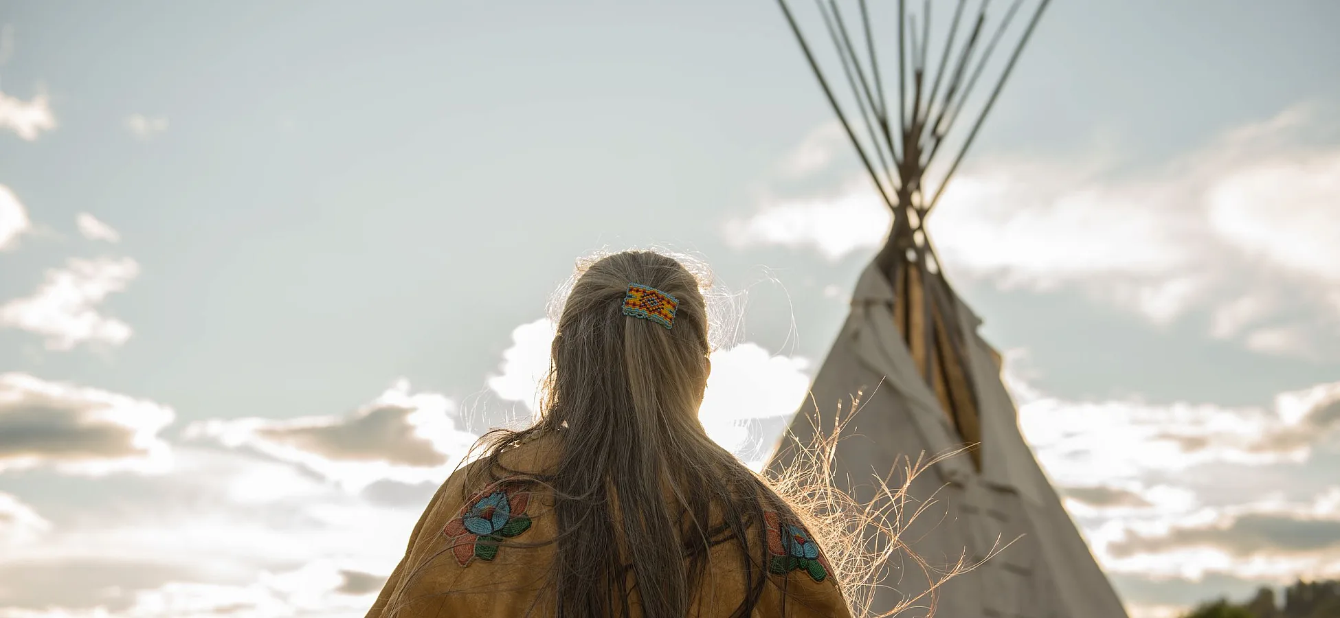 Ktunaxa elder in regalia next to a teepee at St Eugene Golf Resort