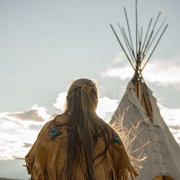 Ktunaxa elder in regalia next to a teepee at St Eugene Golf Resort