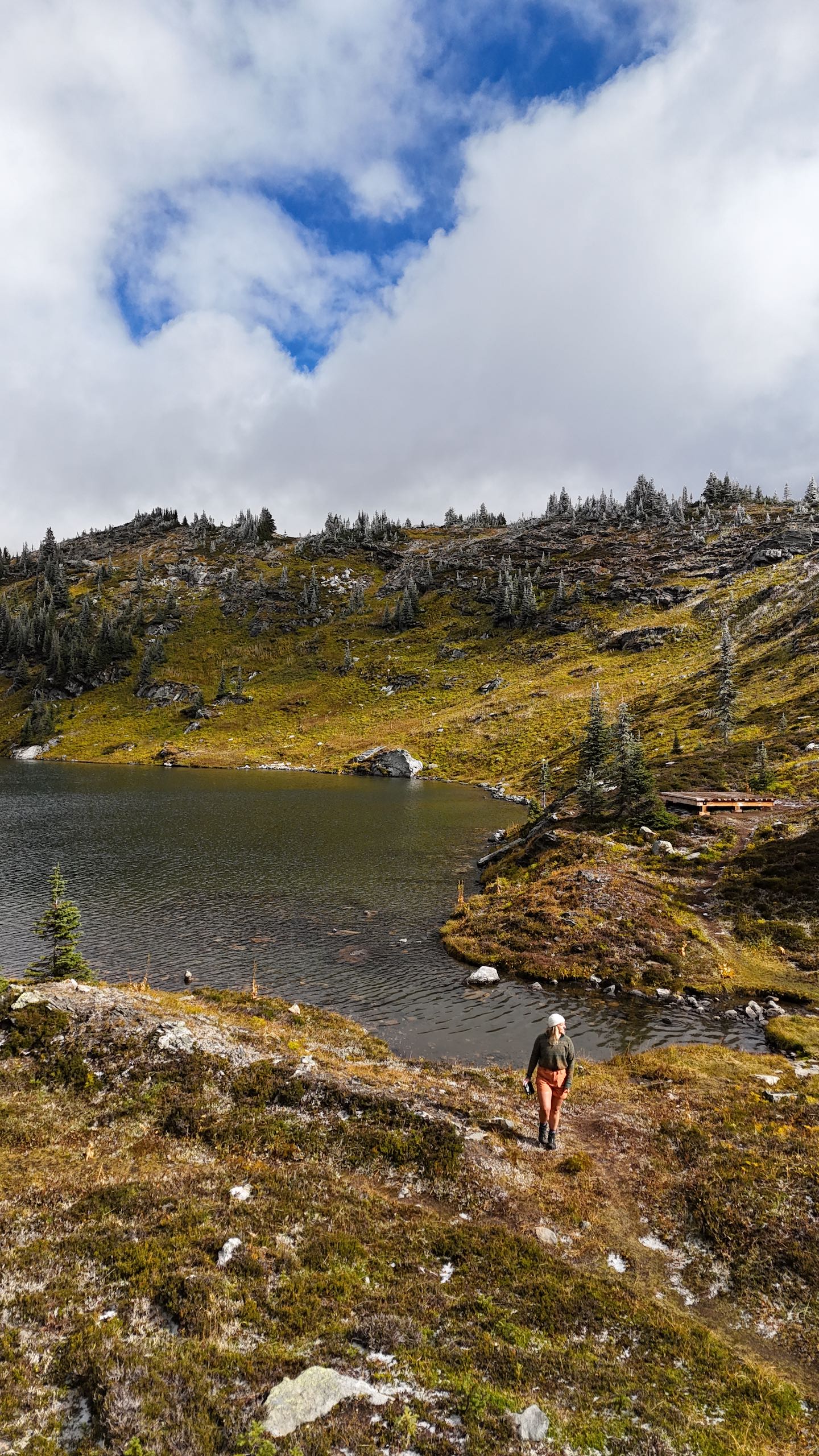 A drone shot of a person walking on a trail on Trophy Mountain with Sheila Lake in the background.