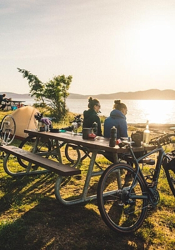 Two people sitting at a picnic table enjoying the ocean view at Ruckle Provincial Park during a bike-packing trip on Salt Spring Island.