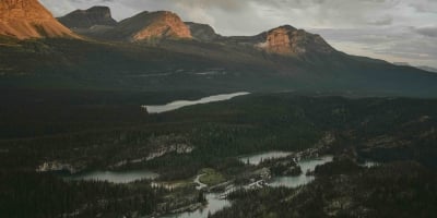 A mountain range at sunset in the Northern Rockies. A river system flows in the valley below.