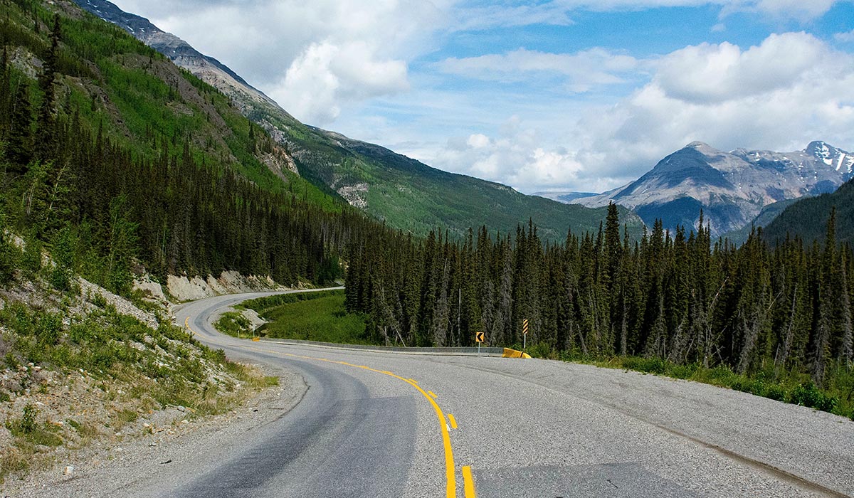 A winding road leads to snow capped mountains in Alaska.