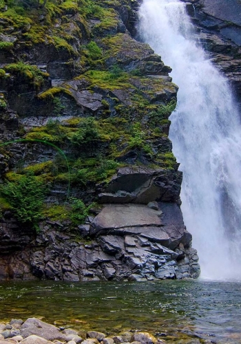 A waterfall and a person at the bottom looking up