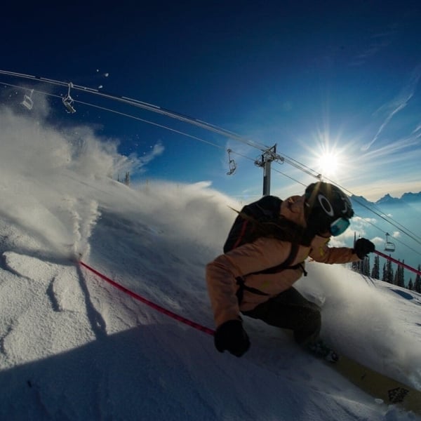 A close up of a skier on a deep turn with the chair lift behind them