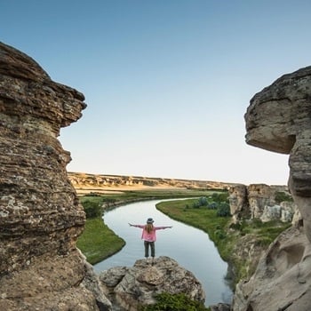 A person standing between two stone structures at Writing-On-Stone Provincial Park