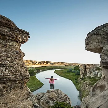 Una persona parada entre dos estructuras de piedra en Writing-On-Stone Provincial Park.