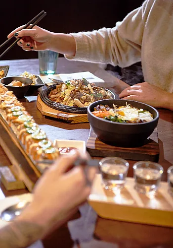 Un primer plano de las manos de dos personas mientras comen en el restaurante Sooda Korean BBQ en Brentwood Town Centre en Burnaby.