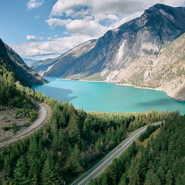 lago turquesa rodeado de bosque en primer plano y artemisa al fondo.