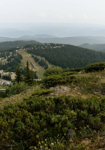 People trail running up SilverStar Mountain, with SilverStar Mountain Resort village in the background